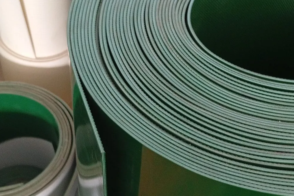 Penampang gulungan belt PVC hijau, lapisan-lapisannya tersusun rapat memperlihatkan ketebalan belt